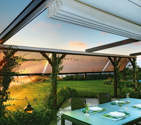 Outdoor dining table protected by a retractable pergola